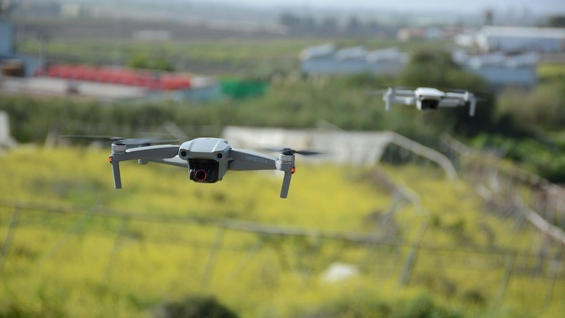 Schwarz-weiße Drohne, die über einem grünen offenen Feld fliegt.
